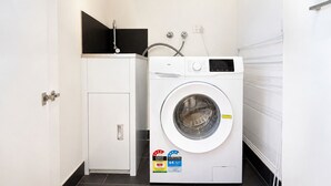 Uma lavanderia compacta com máquina de lavar frontal, um pequeno armário e um aquecedor de água.