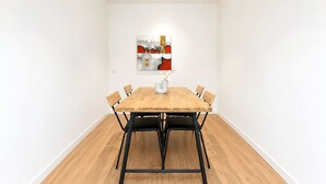 Uma sala de jantar com uma mesa de madeira, seis cadeiras e um vaso com flores.