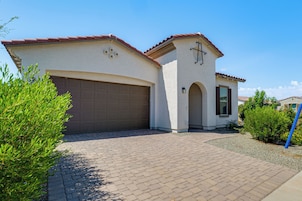 A two-story house with a garage, a small porch, and a well-maintained garden.