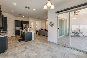 A modern kitchen with dark cabinets, a central island, and a dining area with a sofa and chairs. - Wfh-friendly Queen Creek Retreat w/ Pool Access (Queen Creek)