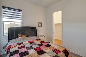 A bedroom with a bed, a window with blinds, a door, and a small bedside table. - Wfh-friendly Queen Creek Retreat w/ Pool Access (Queen Creek)