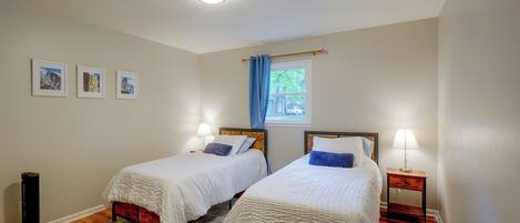 Une chambre avec deux lits, une fenêtre avec des rideaux bleus et un luminaire au plafond.