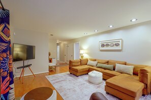 A living room with a sofa set, a flat-screen TV, a lamp, and a framed picture on the wall. - Fire Pit & Grill! Wooded Durham Retreat (Durham)