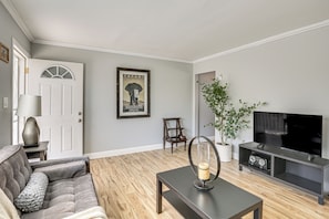 A living room with a sofa, a coffee table, a television, a framed picture on the wall, and a potted plant. - 5 Mi to Sdsu & Trails! Stylish Apartment w/ Patio (San Diego)