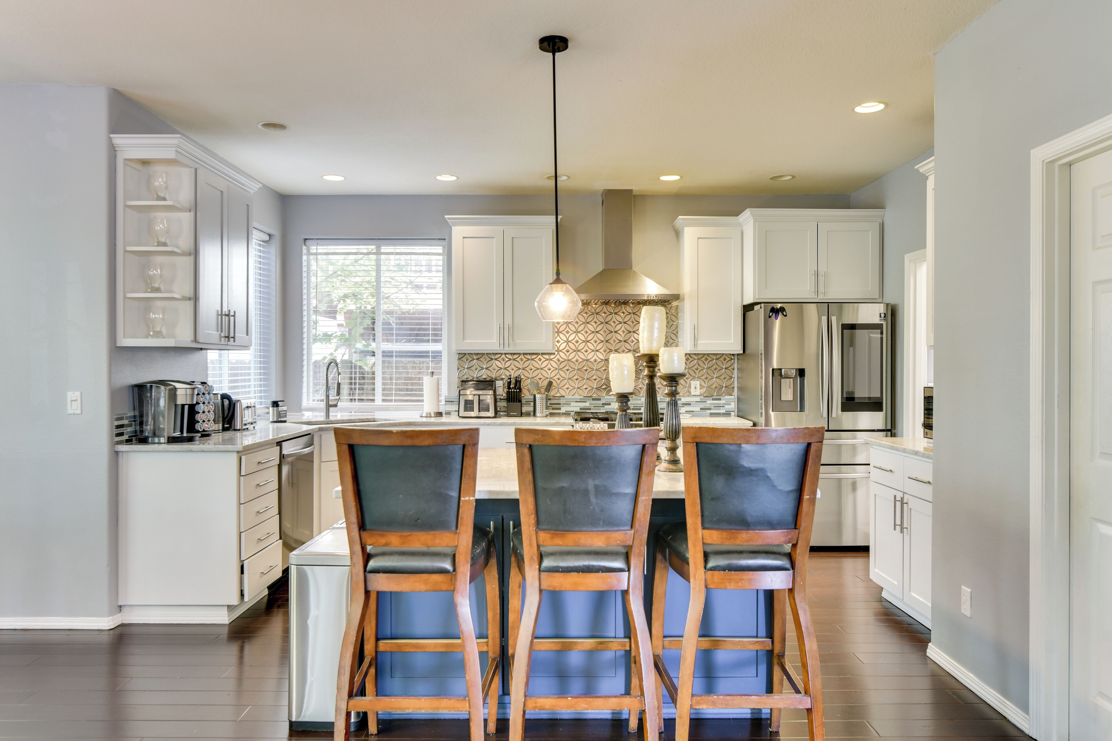 A modern kitchen with a central island, stainless steel appliances, and a pendant light.