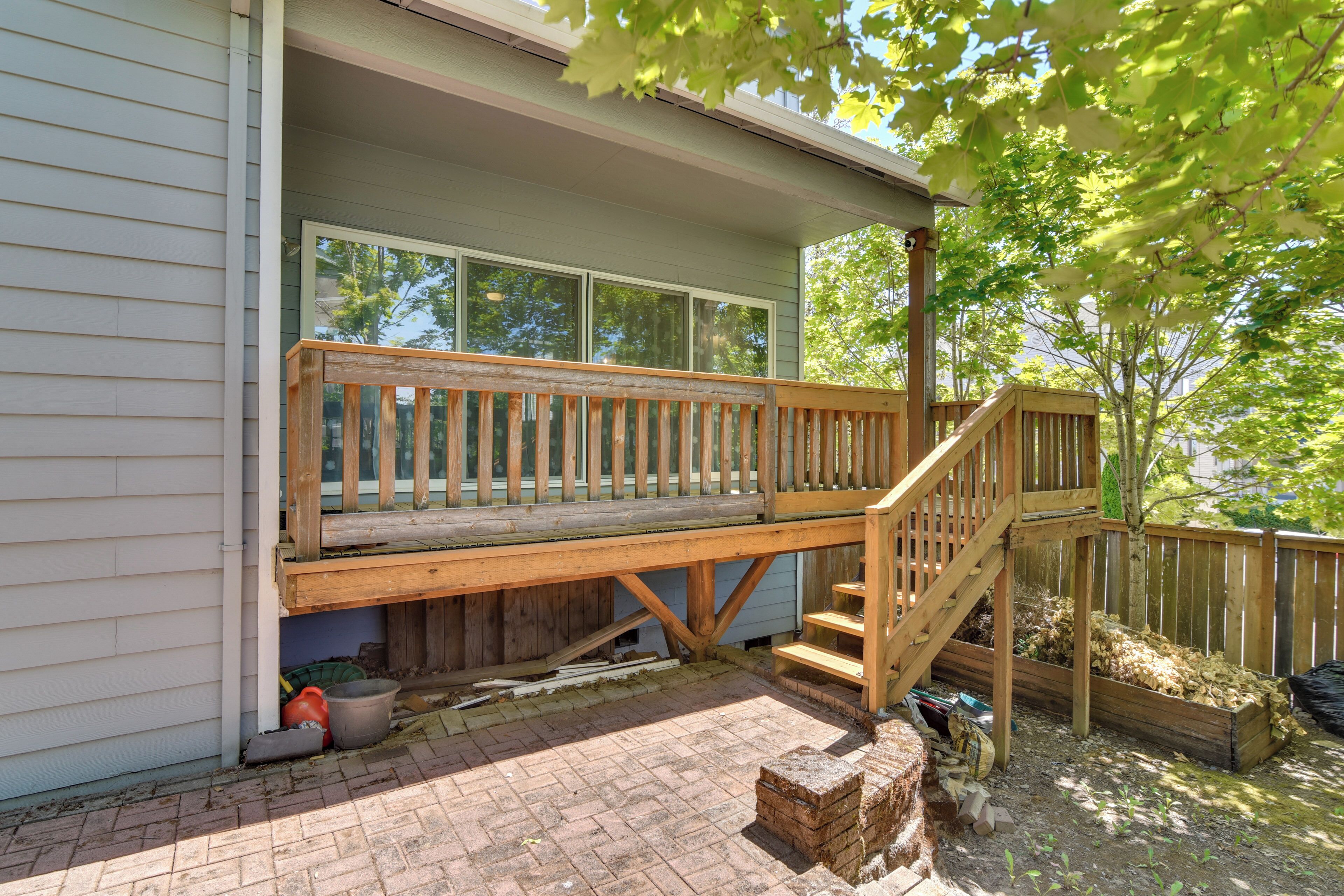 A wooden deck attached to a house with a brick pathway leading to it.