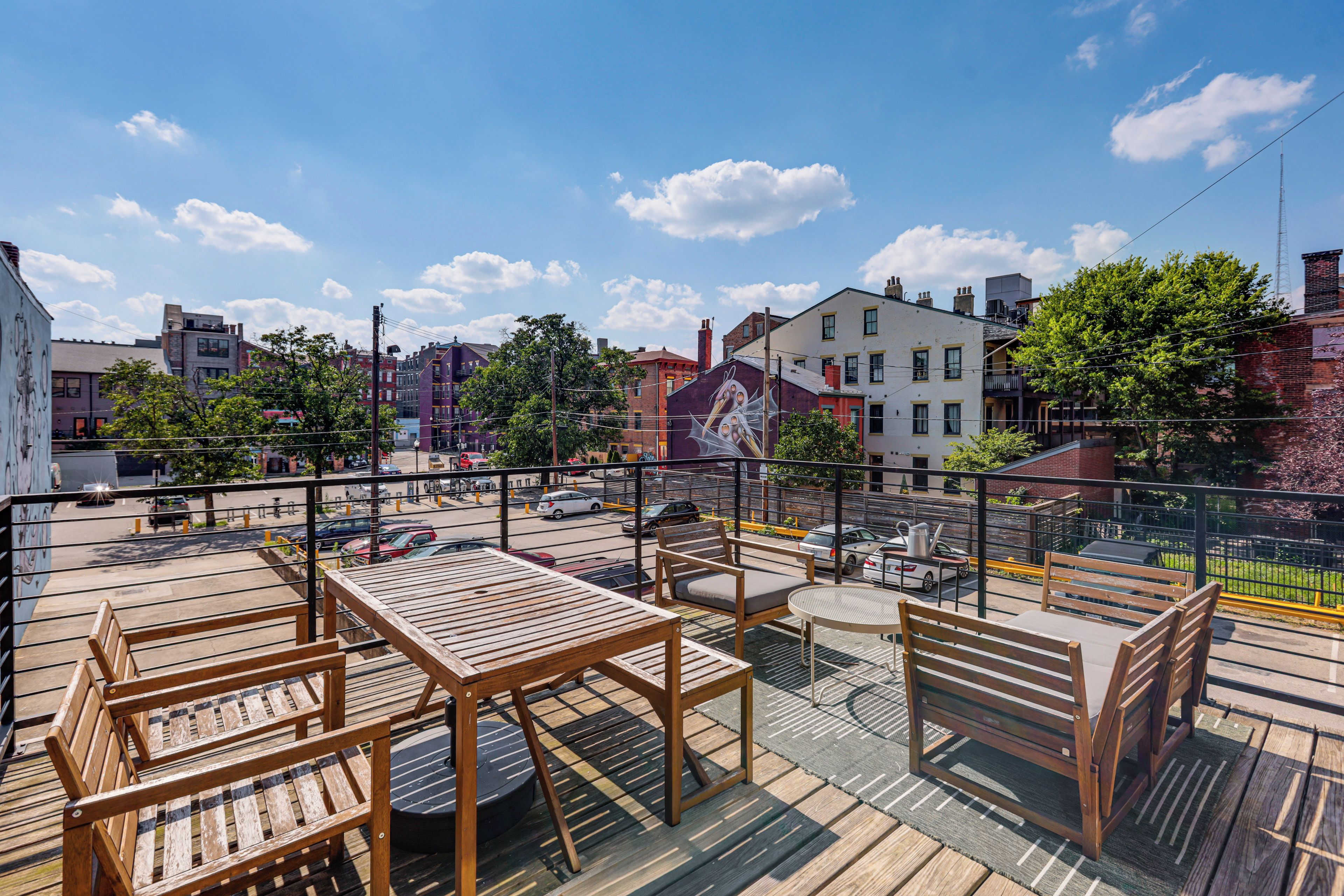 A rooftop terrace with wooden furniture and a view of the cityscape.