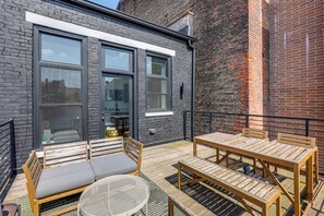 An outdoor patio with wooden furniture, including a table and chairs, and a round metal table. - Walk to Findlay Market! Over-the-rhine Condo (Cincinnati)