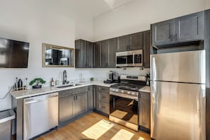 A modern kitchen with stainless steel appliances, dark wood cabinets, and a large mirror. - Walk to Findlay Market! Over-the-rhine Condo (Cincinnati)