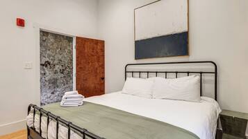 Um quarto com uma cama, uma porta e um quadro na parede.