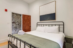 Ein Schlafzimmer mit einem Bett, einer Tür und einem Bild an der Wand.