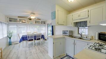 A kitchen with white cabinets, a gas stove, a microwave, and a dining area with a table and chairs.