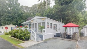 A single-story mobile home with a porch, a covered outdoor seating area, and a small garden. - 2 Decks & Pool Access: Ocean Pines Retreat (Berlin)