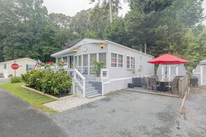 A single-story mobile home with a porch, a covered outdoor seating area, and a small garden. - 2 Decks & Pool Access: Ocean Pines Retreat (Berlin)
