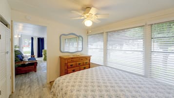 A bedroom with a bed, dresser, mirror, and a ceiling fan.
