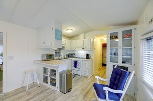 A compact kitchen with white cabinets, a built-in oven, a microwave, and a coffee maker.