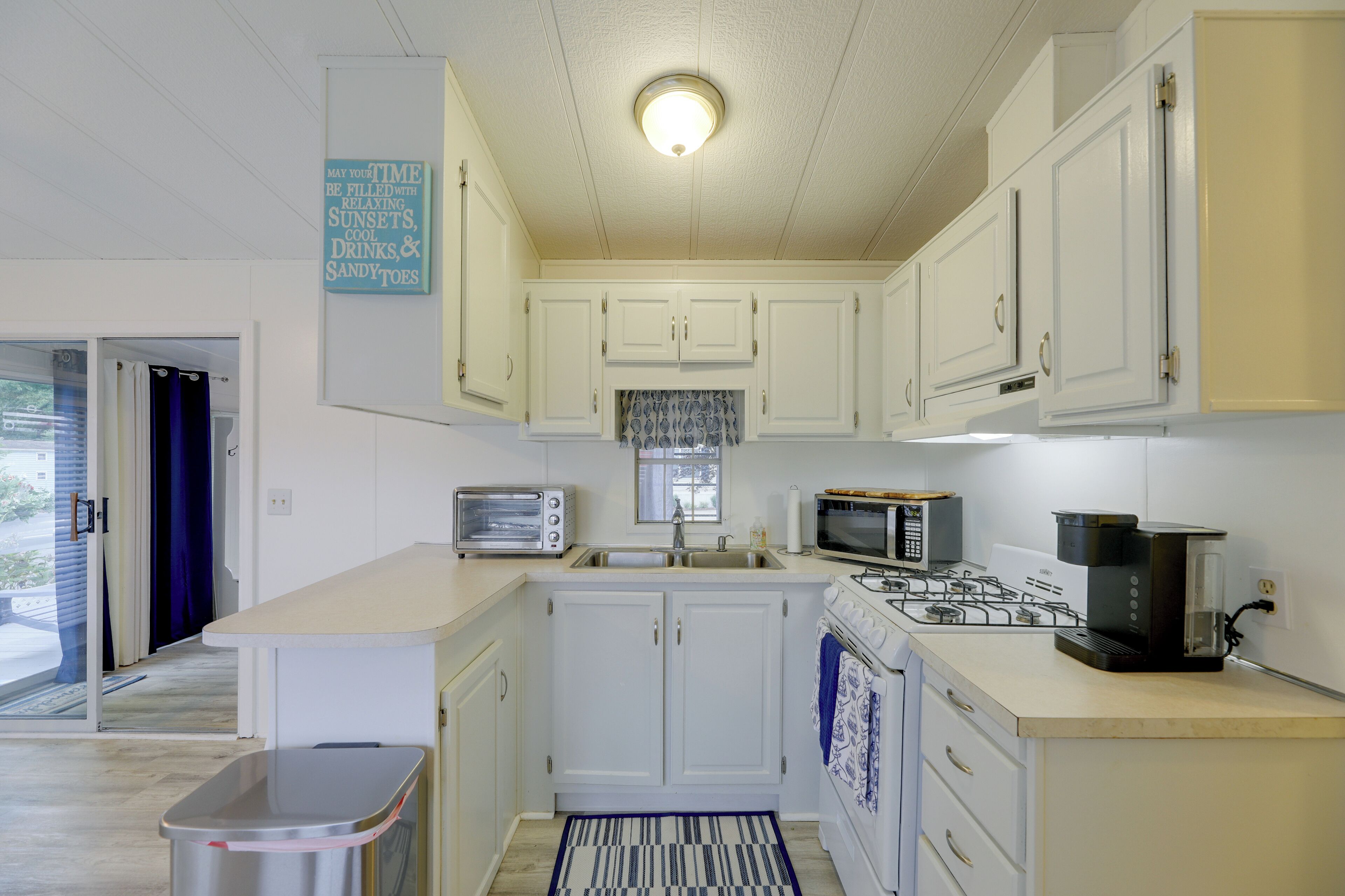 A compact kitchen with white cabinets, a built-in microwave, a gas stove, and a toaster.