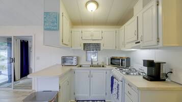 A compact kitchen with white cabinets, a built-in microwave, a gas stove, and a toaster.
