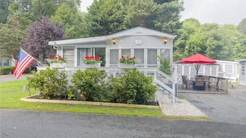 A small, single-story building with a porch, a flag, and a sign that reads 'Welcome to Summer Sea.'