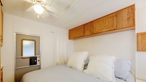 A bedroom with a bed, a ceiling fan, wooden cabinets, and a window with blinds. - 2 Decks & Pool Access: Ocean Pines Retreat (Berlin)