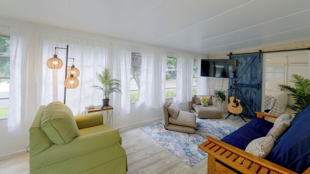 A spacious living room with a green armchair, a sofa, a wooden coffee table, and a guitar. - 2 Decks & Pool Access: Ocean Pines Retreat (Berlin)