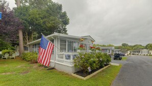 A single-story house with a front porch, a flag, and a garden with flowers. - 2 Decks & Pool Access: Ocean Pines Retreat (Berlin)