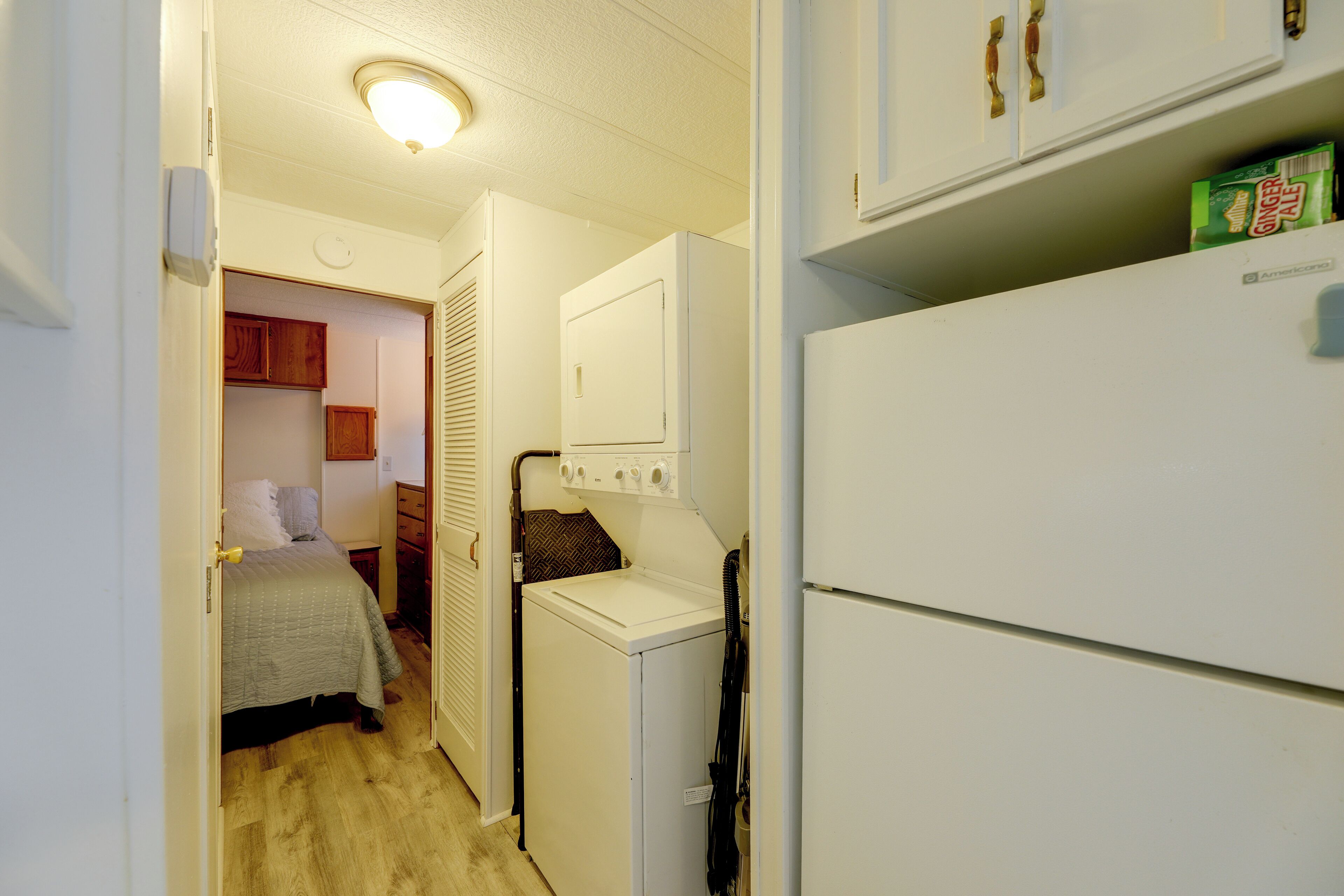 A compact laundry room with a washing machine, dryer, and a small cabinet with a green box on top.