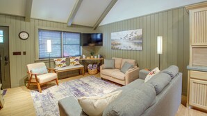 Ein Wohnzimmer mit einer Sofagarnitur, einem Fernseher und einem Bild an der Wand.