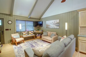 Ein Wohnzimmer mit einer Sofagarnitur, einem Fernseher und einem Bild an der Wand.