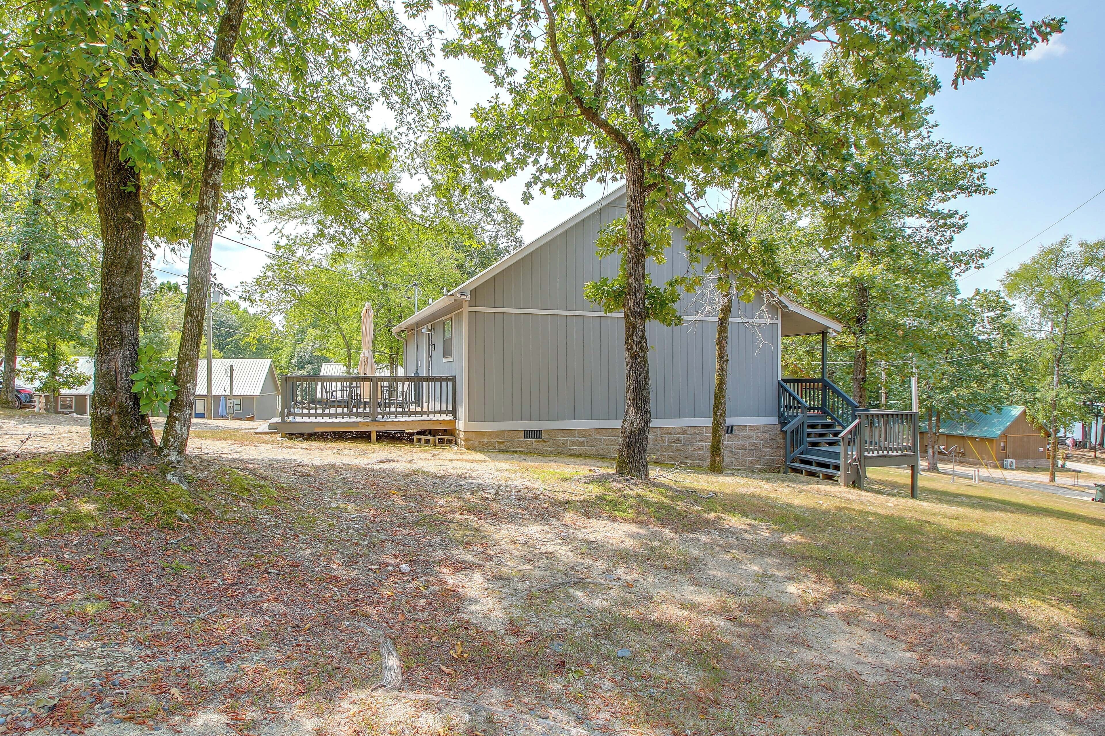 A cabin with a deck, surrounded by trees, and a clear sky.