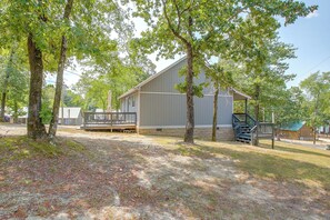 A cabin with a deck, surrounded by trees, and a clear sky.