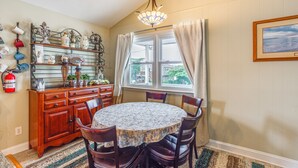 A dining area with a round table, chairs, a wooden cabinet, and a window with curtains. - Walk to Beach & Marinas! Brigantine 2-unit Duplex (Brigantine)