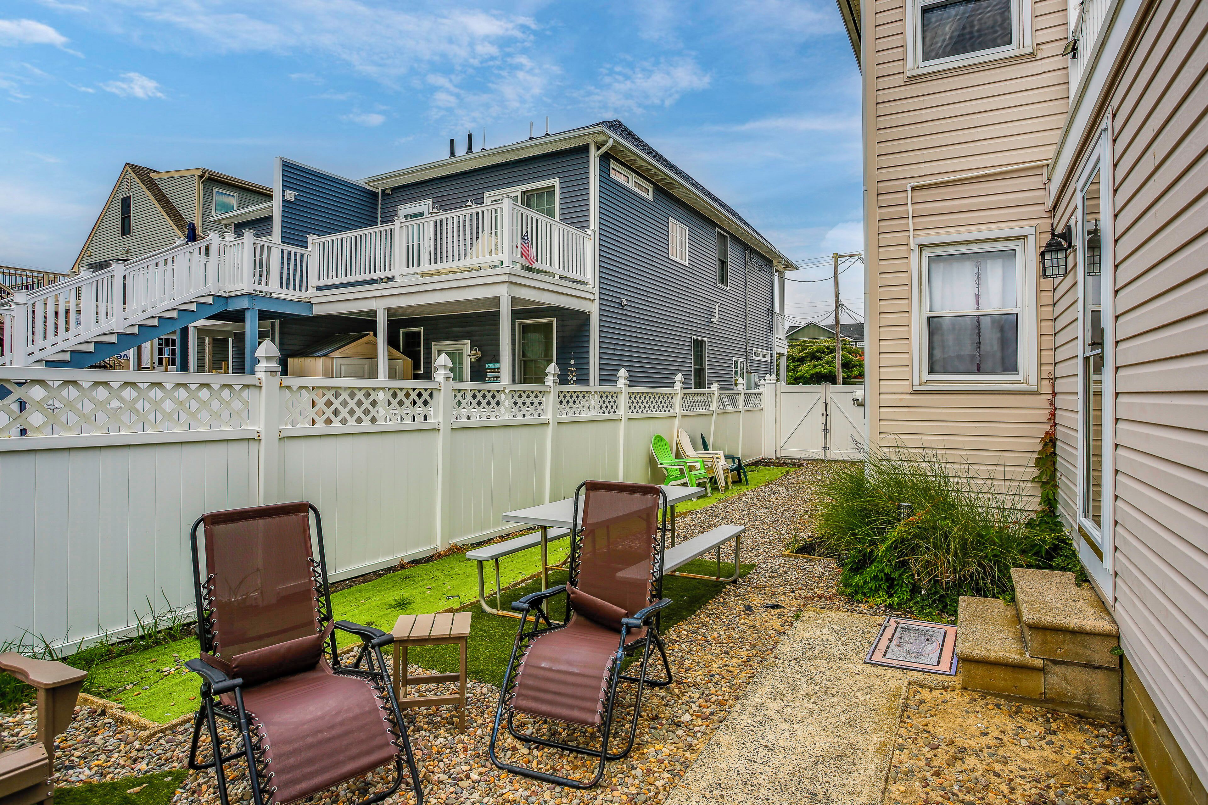 A two-story house with a balcony, outdoor seating, and a small garden.