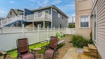 A two-story house with a balcony, outdoor seating, and a small garden.