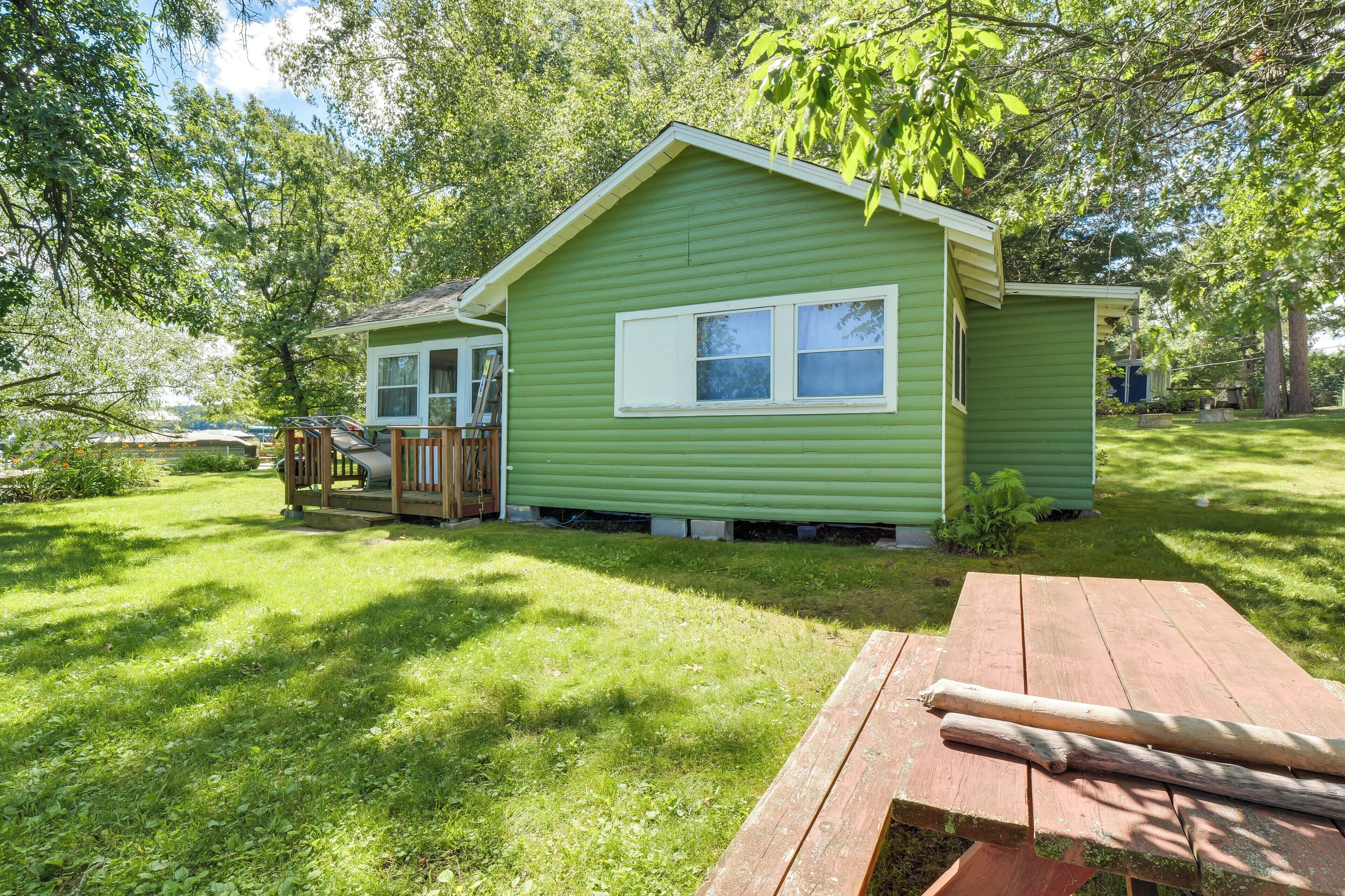 Een groen huis met één verdieping, een veranda en een picknicktafel.