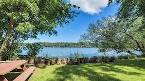 A picnic table and a grassy area with a view of a lake and trees. - Pet-friendly Rustic Cabin Steps From Lake Chetek (Chetek)