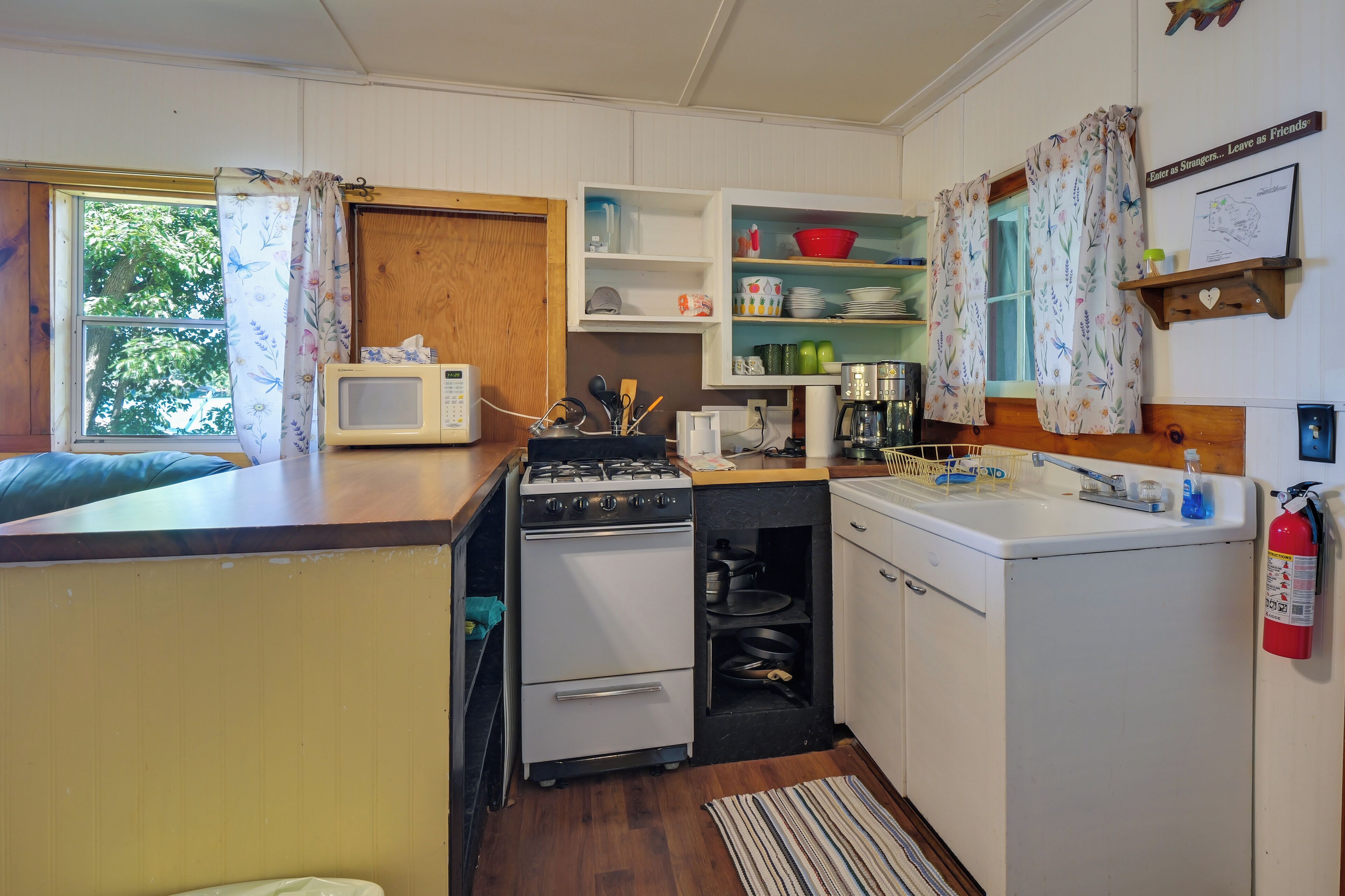 A compact kitchen with a microwave, stove, oven, and sink.