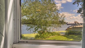 A window view of a lake with a tree and a boat dock. - Pet-friendly Rustic Cabin Steps From Lake Chetek (Chetek)