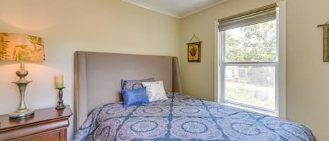 A bedroom with a bed, dresser, lamp, and window.