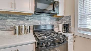 A kitchen with a gas stove, a microwave, and a coffee maker.