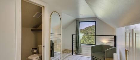 Une salle de bain avec des toilettes, un miroir et une fenêtre donnant sur un espace verdoyant.
