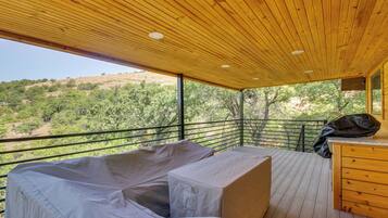A covered outdoor seating area with a view of a hilly landscape.