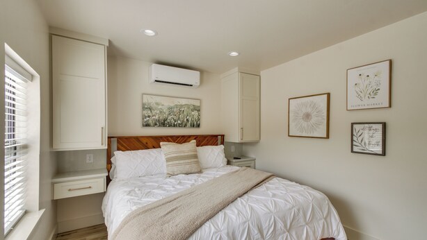 A bedroom with a bed, a nightstand, a dresser, an air conditioning unit, and wall art. - Mtn-view Deck w/ Grill! Modern Medicine Park Cabin (Medicine Park)