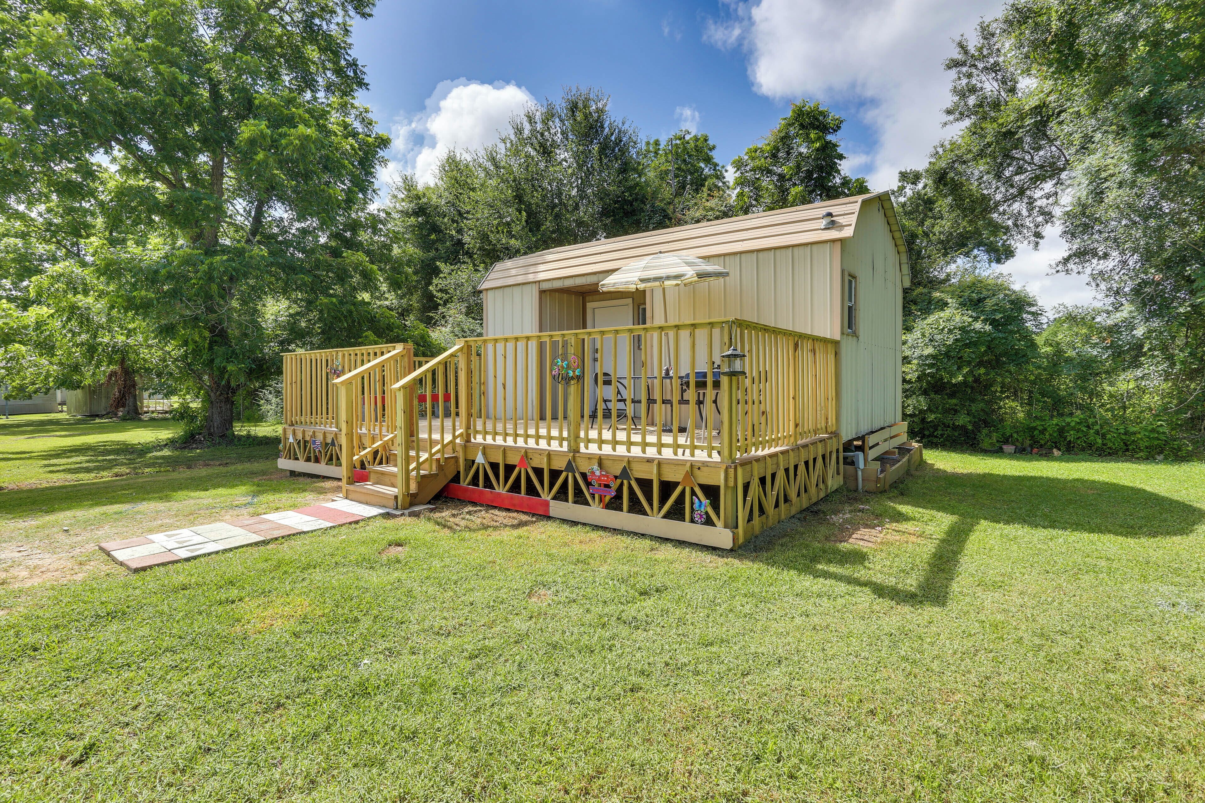 A wooden cabin with a deck, surrounded by trees.