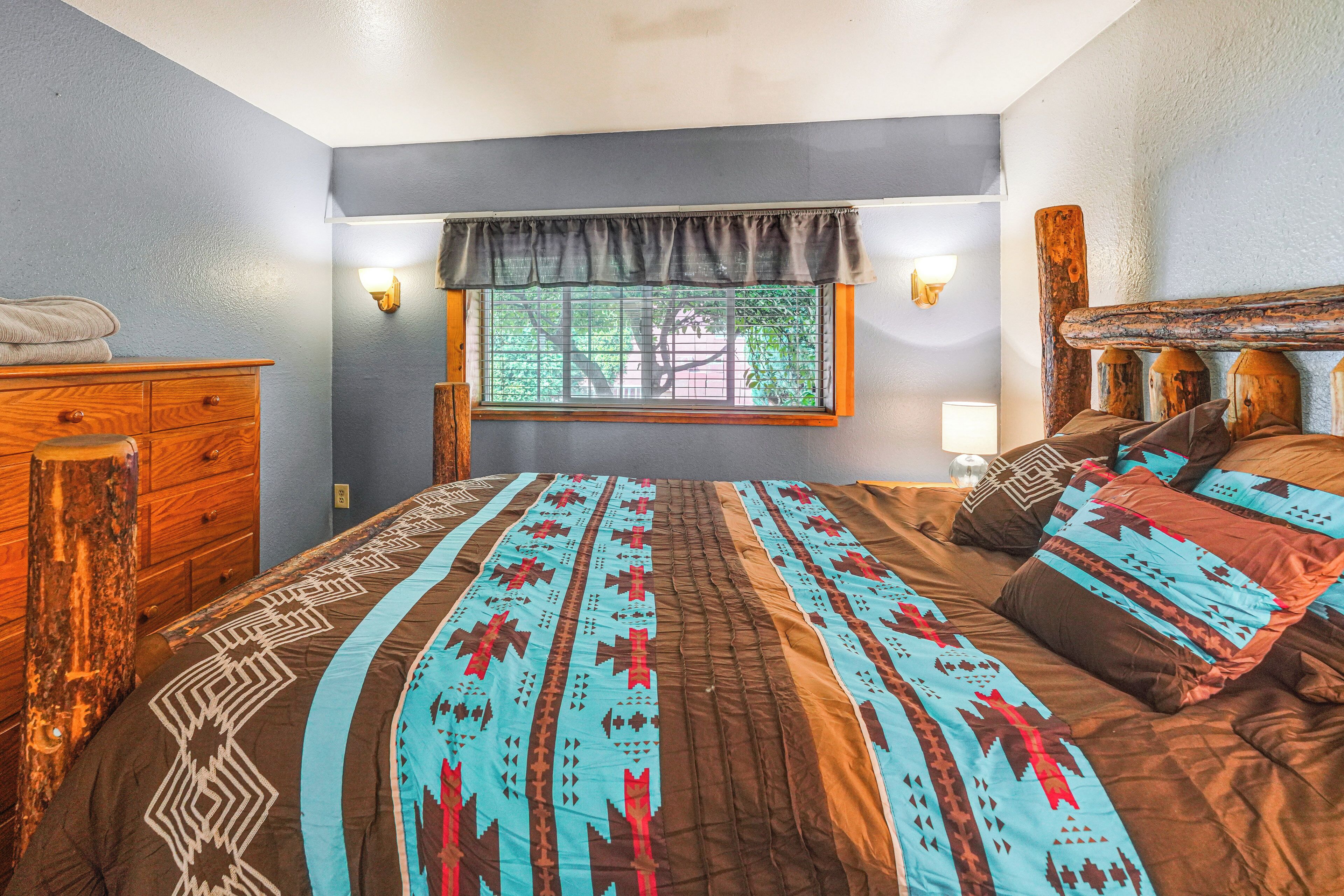 A bedroom with a large bed, wooden headboard, and a window with blinds.