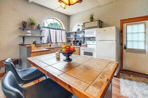 A compact kitchen with a dining table, chairs, a refrigerator, and a microwave.