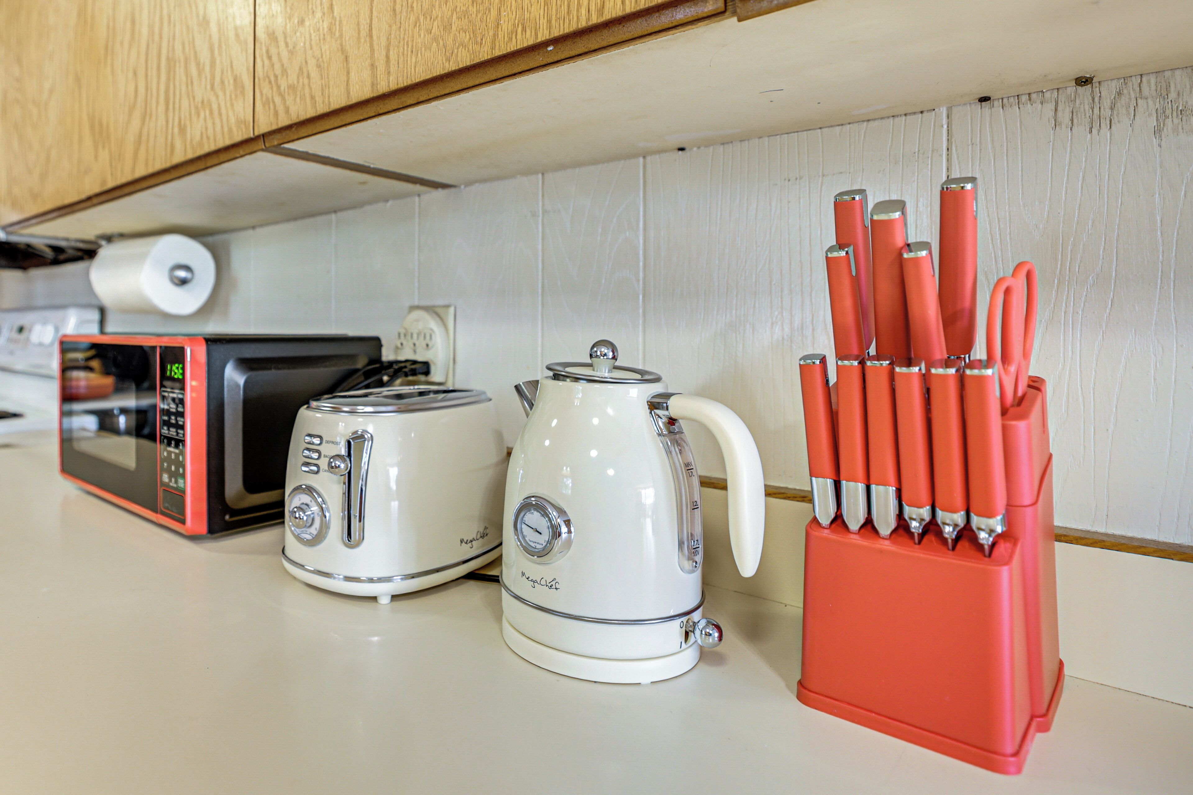 A kitchen counter with a toaster, a kettle, and a knife holder.