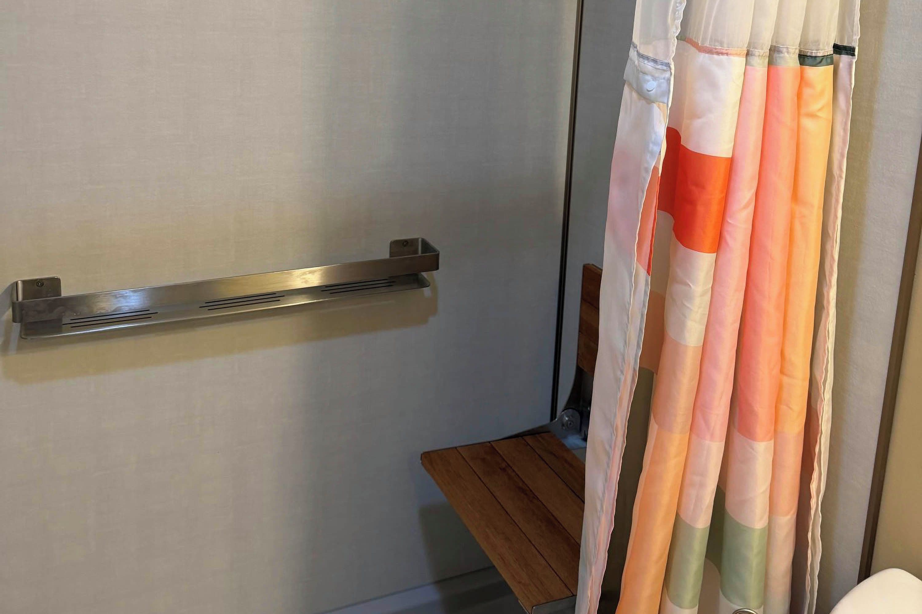 Une salle de bain avec un rideau de douche, un porte-serviettes et un banc en bois.