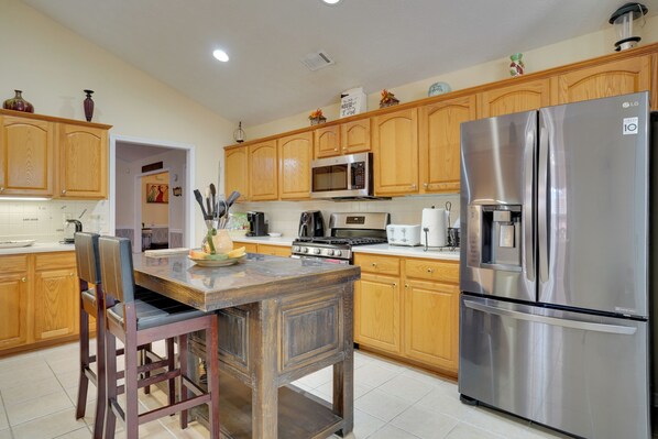 A kitchen with wooden cabinets, a stainless steel refrigerator, a microwave, and a stove. - Hot Tub & Deck! Loganville Group Retreat (Loganville)