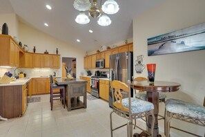 A modern kitchen with wooden cabinets, stainless steel appliances, and a dining area with a round table and chairs. - Hot Tub & Deck! Loganville Group Retreat (Loganville)